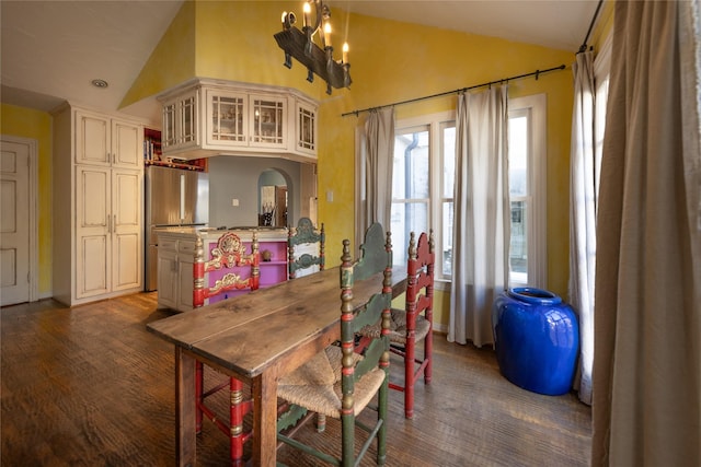 dining room with an inviting chandelier, high vaulted ceiling, and dark wood-type flooring