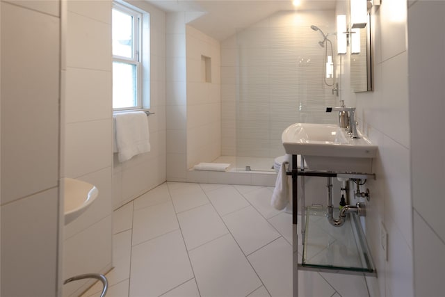 bathroom featuring sink, tile patterned flooring, vaulted ceiling, tiled shower, and tile walls