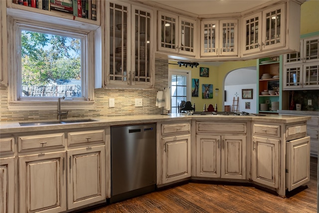 kitchen featuring dishwasher, backsplash, sink, dark hardwood / wood-style floors, and kitchen peninsula