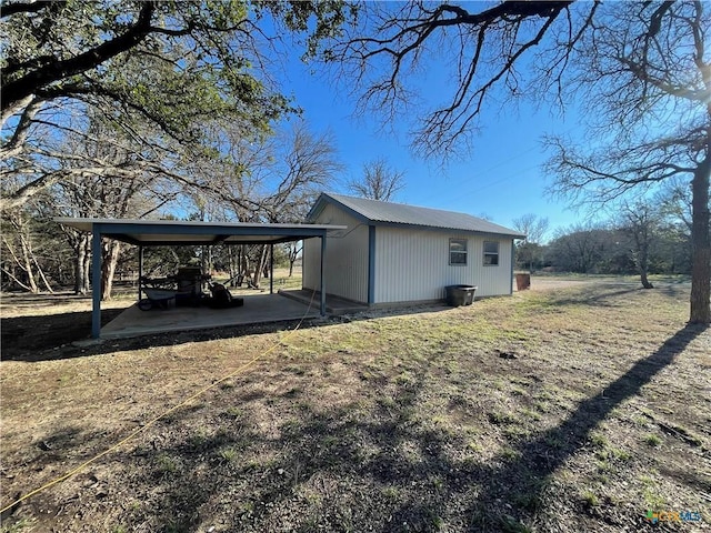 exterior space with metal roof, a carport, and a yard