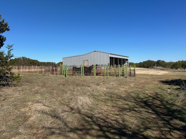 view of pole building featuring an exterior structure, a rural view, and fence