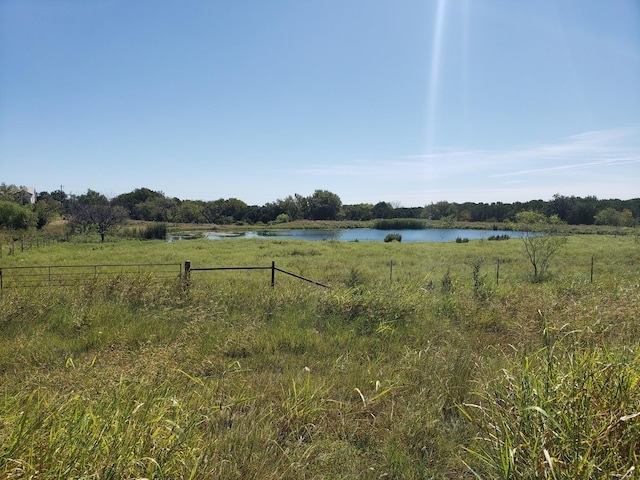 view of yard featuring a water view, fence, and a rural view