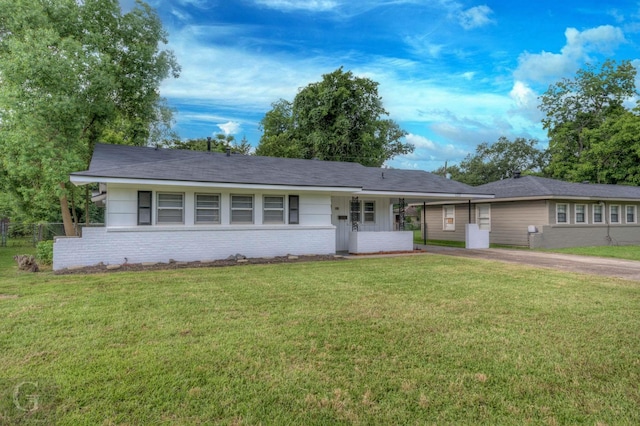 single story home with driveway, an attached carport, brick siding, and a front lawn