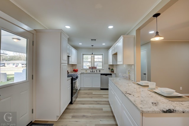 kitchen with stainless steel dishwasher, gas range oven, backsplash, a sink, and light wood-type flooring