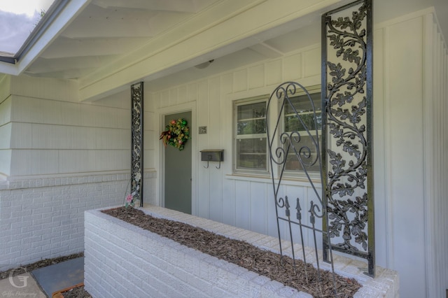 property entrance featuring a porch, board and batten siding, and brick siding