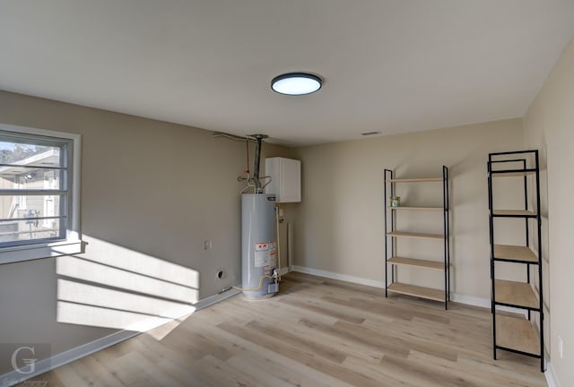 below grade area with gas water heater, light wood finished floors, and baseboards