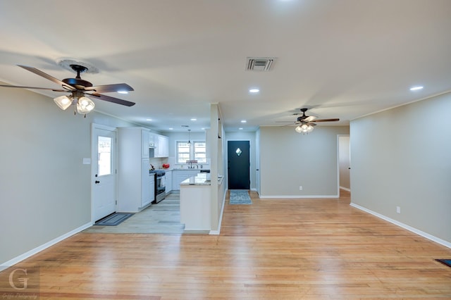 kitchen featuring a ceiling fan, gas stove, white cabinets, light wood-style floors, and open floor plan