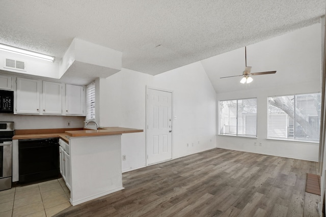 kitchen featuring ceiling fan, stainless steel range oven, kitchen peninsula, a textured ceiling, and white cabinets