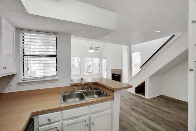 kitchen featuring kitchen peninsula, sink, white cabinets, and a textured ceiling