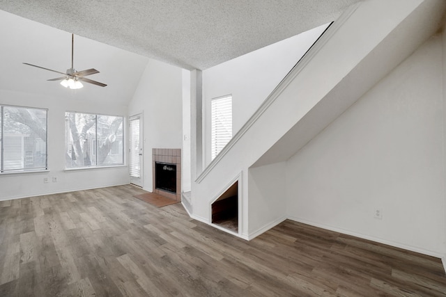 unfurnished living room with hardwood / wood-style floors, a textured ceiling, high vaulted ceiling, and ceiling fan