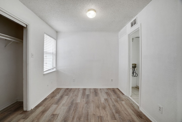 unfurnished bedroom with a textured ceiling, light hardwood / wood-style floors, and a closet