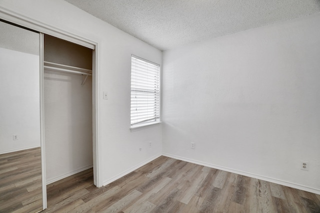 unfurnished bedroom with a closet, light hardwood / wood-style floors, and a textured ceiling