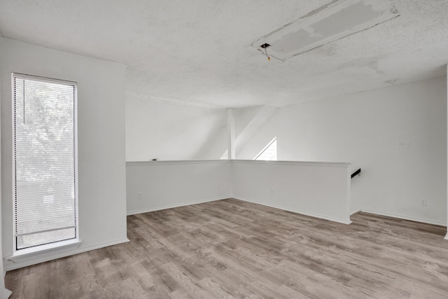 spare room with light wood-type flooring and a textured ceiling