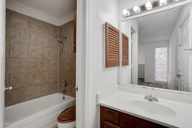 full bathroom with a textured ceiling, vanity, toilet, and tiled shower / bath