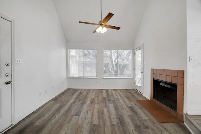 unfurnished living room with high vaulted ceiling, ceiling fan, wood-type flooring, and a tile fireplace