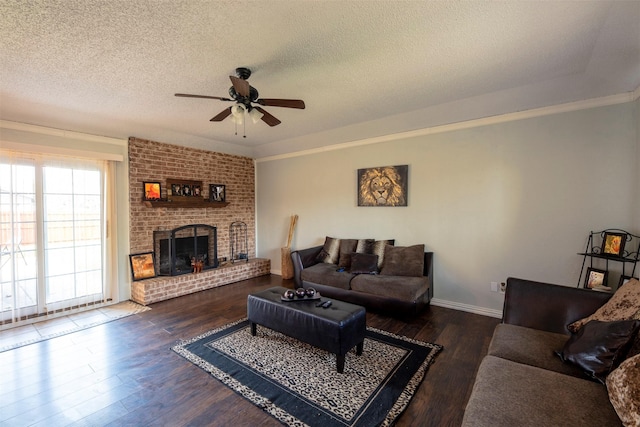 living room featuring ceiling fan, a brick fireplace, dark hardwood / wood-style floors, a textured ceiling, and ornamental molding