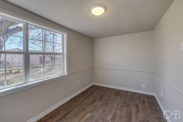 empty room with plenty of natural light, dark hardwood / wood-style floors, and a textured ceiling