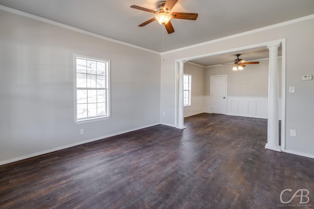 empty room featuring dark wood-type flooring, decorative columns, ceiling fan, and ornamental molding