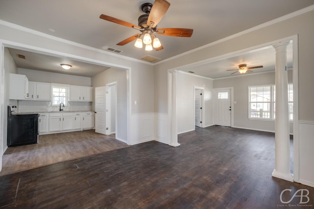 unfurnished living room featuring dark hardwood / wood-style floors, plenty of natural light, ornate columns, and sink