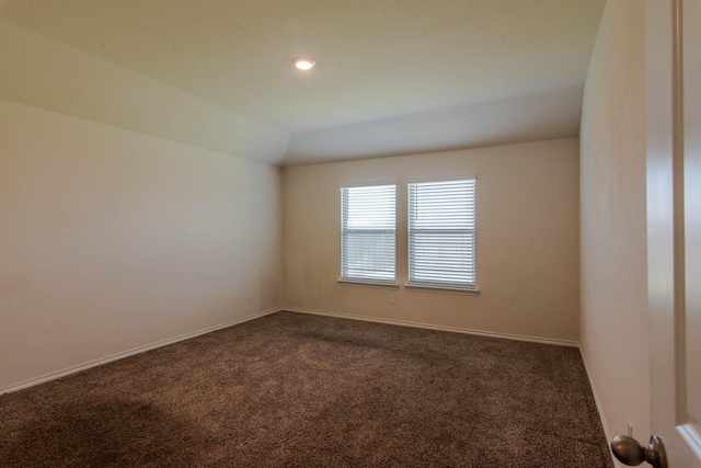 unfurnished room featuring dark colored carpet and lofted ceiling