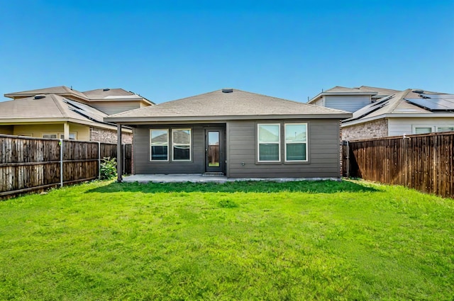 rear view of property with a patio, a lawn, and a fenced backyard