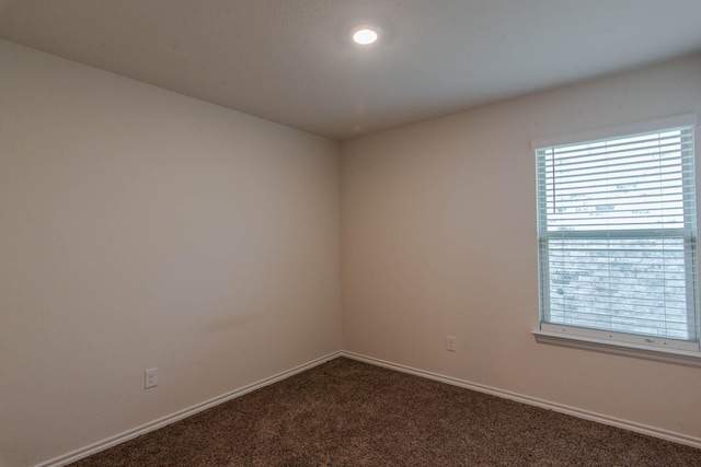 spare room featuring dark colored carpet