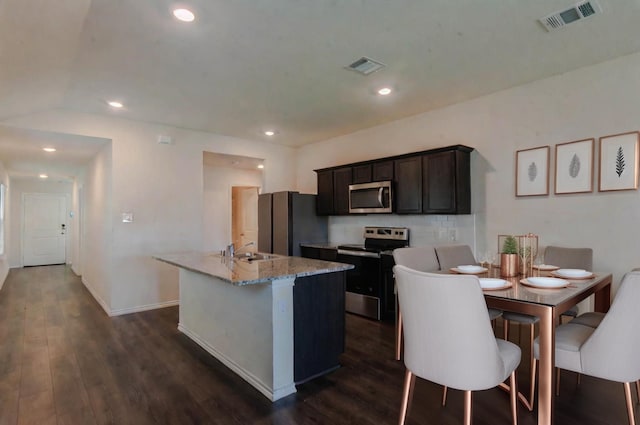 kitchen with visible vents, a kitchen island with sink, appliances with stainless steel finishes, and dark wood-type flooring