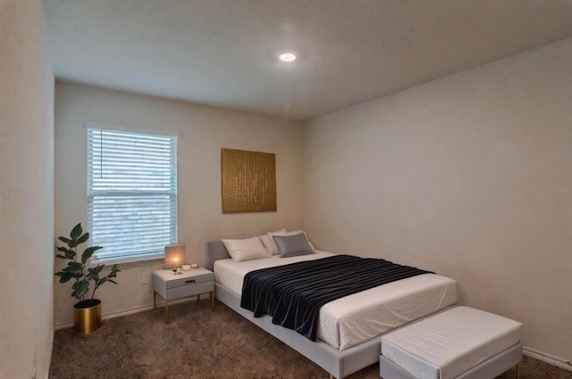 bedroom with baseboards and dark carpet