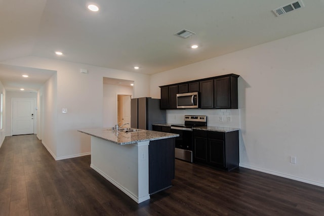 kitchen featuring light stone counters, an island with sink, tasteful backsplash, dark hardwood / wood-style flooring, and stainless steel appliances