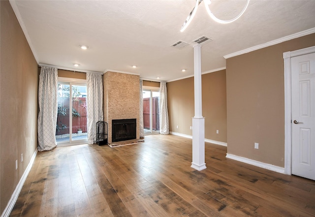 unfurnished living room with decorative columns, crown molding, a large fireplace, and hardwood / wood-style flooring