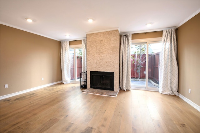 unfurnished living room featuring light hardwood / wood-style floors, a stone fireplace, and ornamental molding