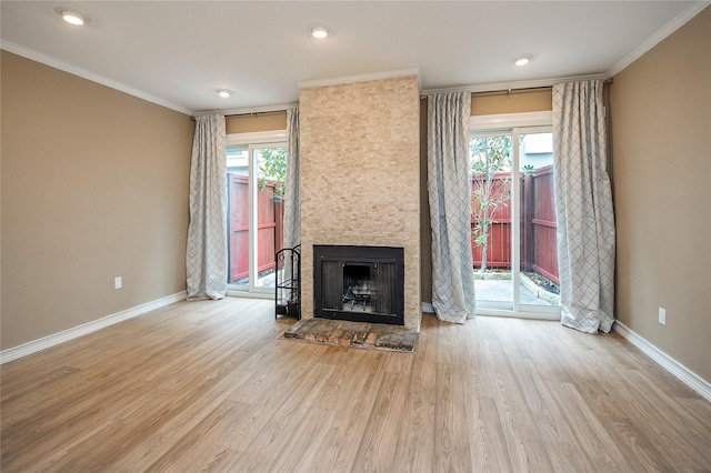 unfurnished living room with crown molding, light hardwood / wood-style flooring, and a large fireplace