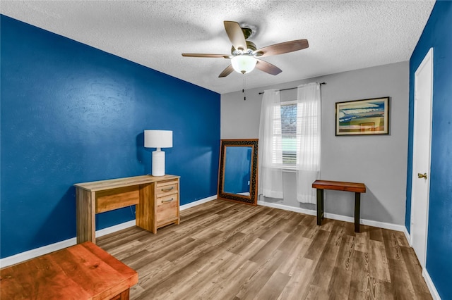 interior space with ceiling fan, wood-type flooring, and a textured ceiling