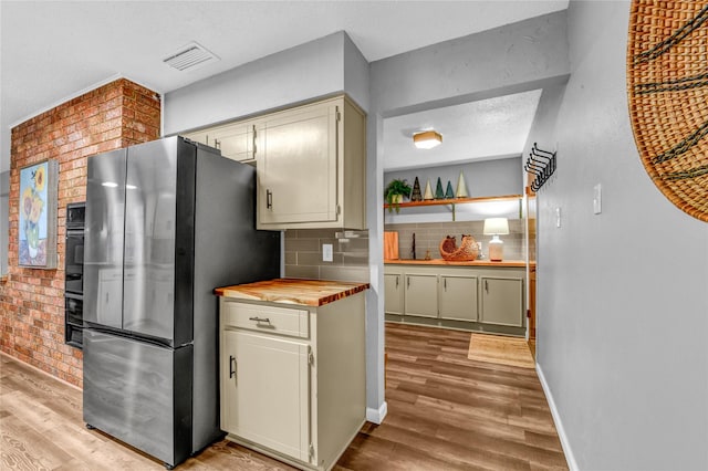 kitchen featuring stainless steel fridge, tasteful backsplash, butcher block countertops, and light hardwood / wood-style flooring