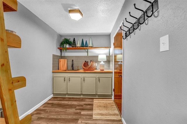 bar featuring decorative backsplash, a textured ceiling, dark wood-type flooring, and sink