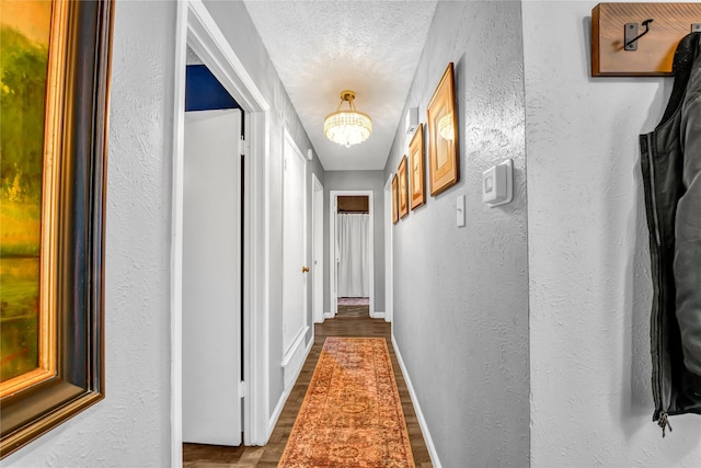 hall with a textured ceiling and a notable chandelier