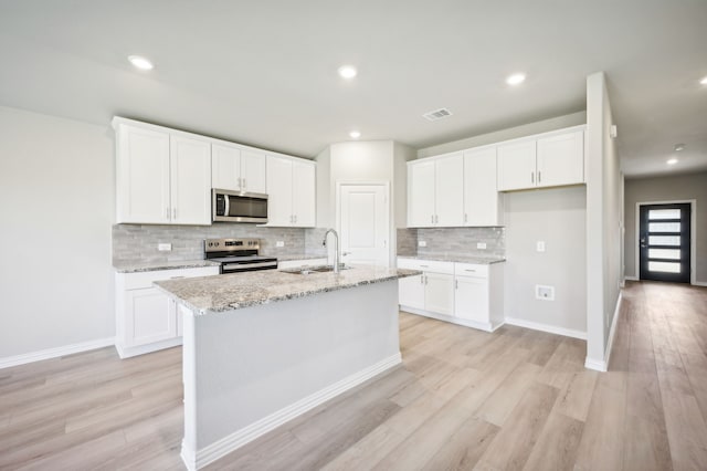 kitchen with sink, white cabinetry, stainless steel appliances, and an island with sink