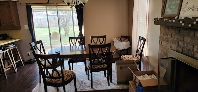 dining area featuring an inviting chandelier, a fireplace, and wood-type flooring