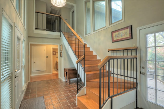 entrance foyer featuring tile patterned floors, a towering ceiling, and an inviting chandelier