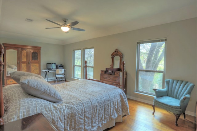 bedroom featuring ceiling fan, light hardwood / wood-style floors, and multiple windows