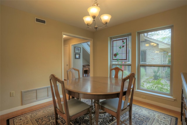 dining room with hardwood / wood-style floors and an inviting chandelier