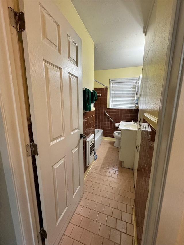 full bathroom featuring  shower combination, tile walls, vanity, heating unit, and toilet