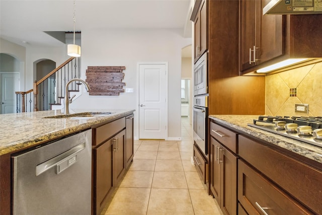 kitchen featuring sink, light tile patterned floors, light stone countertops, appliances with stainless steel finishes, and custom range hood