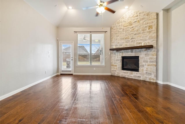 unfurnished living room with a stone fireplace, ceiling fan, dark hardwood / wood-style floors, and vaulted ceiling