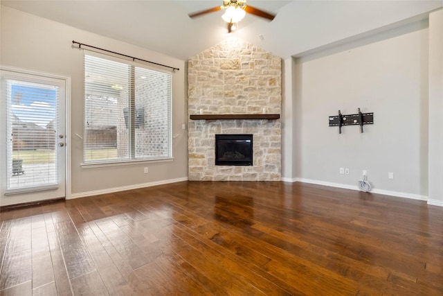 unfurnished living room with dark hardwood / wood-style flooring, vaulted ceiling, ceiling fan, and a stone fireplace