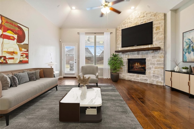 living room with dark hardwood / wood-style flooring, ceiling fan, a stone fireplace, and lofted ceiling