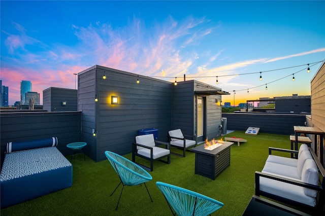 back house at dusk with a lawn and an outdoor living space with a fire pit