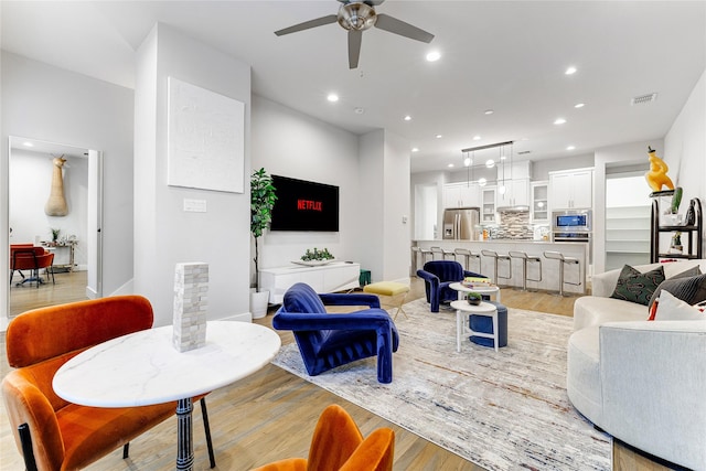 living room featuring light hardwood / wood-style flooring and ceiling fan