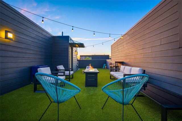 patio terrace at dusk featuring a yard and an outdoor living space with a fire pit