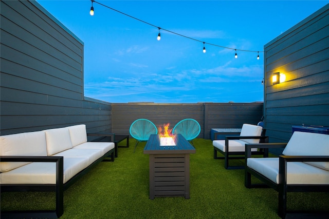 patio terrace at dusk featuring a lawn and an outdoor living space with a fire pit